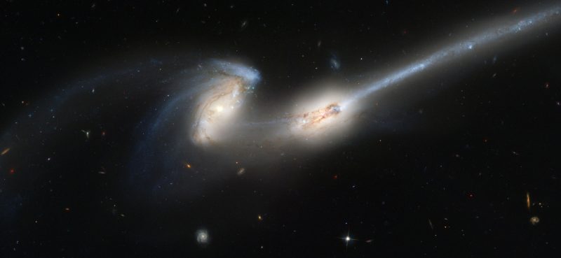 Two galaxies close together stretched irregularly with long streamers of stars.