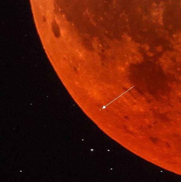 Close-up of a section of the dark orange eclipsed moon, with arrow pointing to tiny meteorite flash.