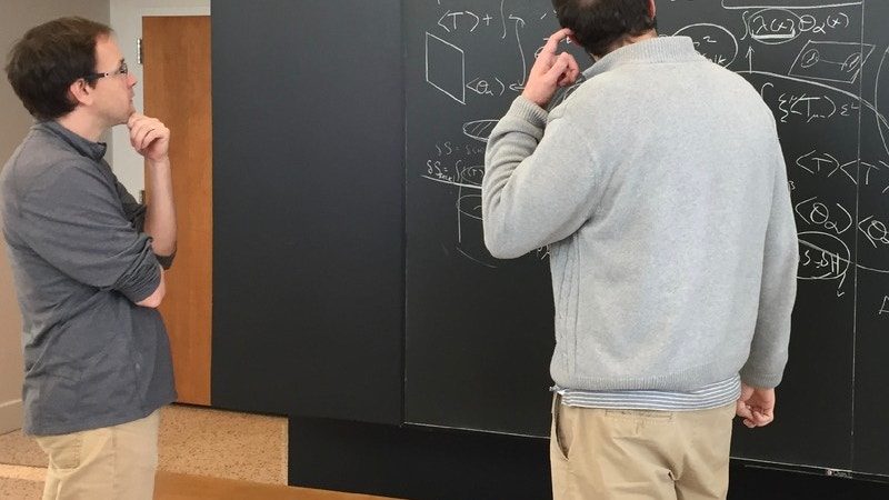 Two physicists looking at a blackboard covered with equations