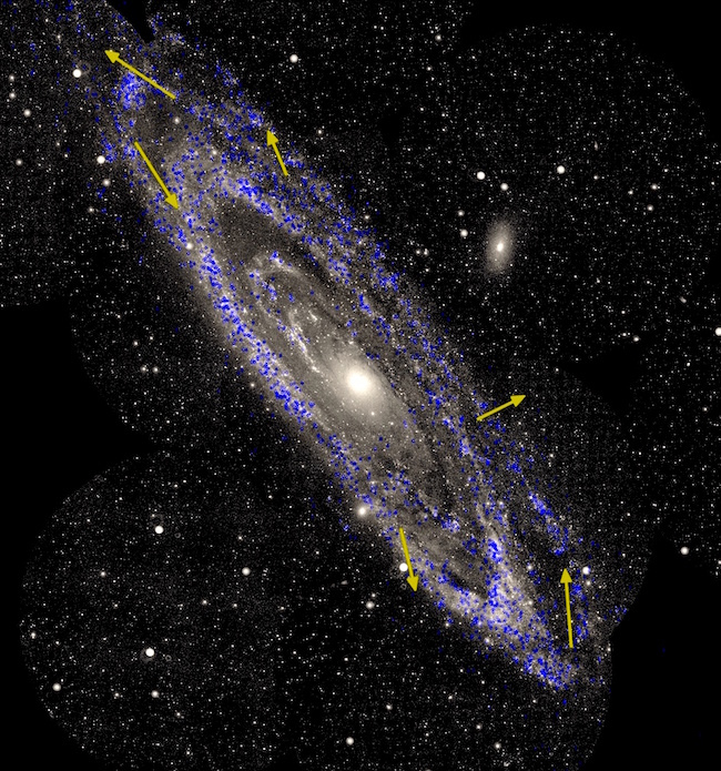 Andromeda galaxy with yellow arrows showing stars moving around and out of the galaxy.