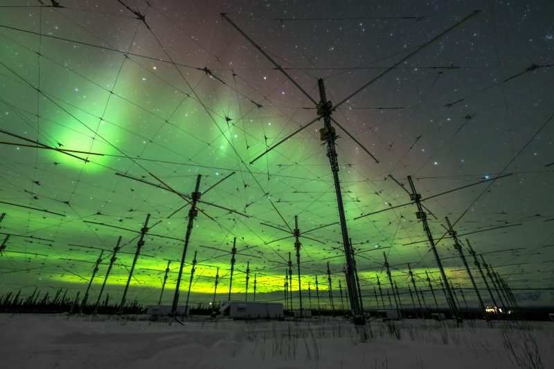 Florescent green aurora. Sky criss-crossed with wires and telephone poles.