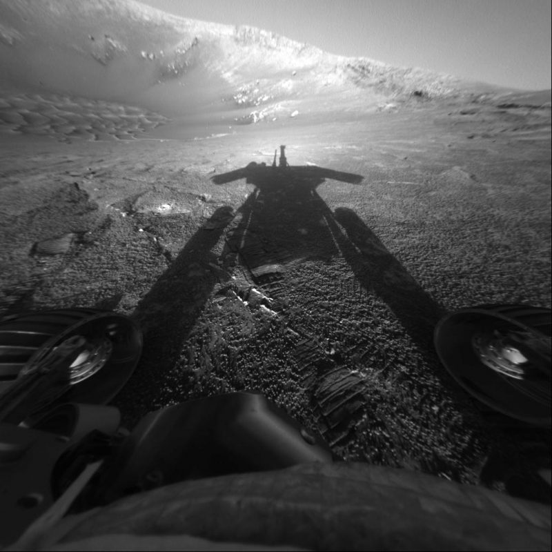 Opportunity: Stretched shadow of machine on rough gray surface, with wheels in foreground.