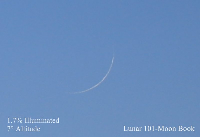 Very thin white crescent in blue sky.