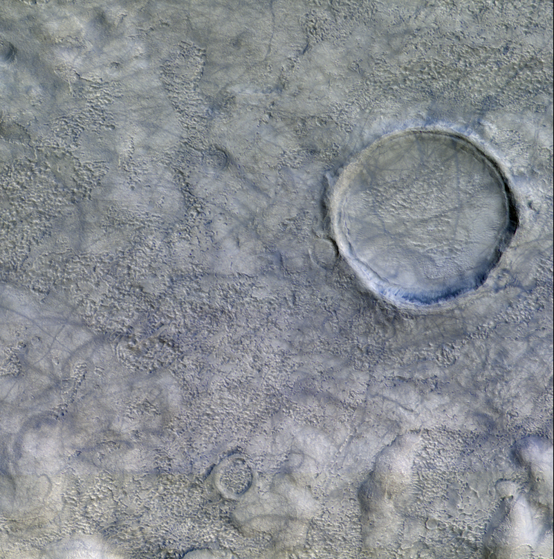 Large crater on gray stippled surface criss-crossed with many bluish lines.