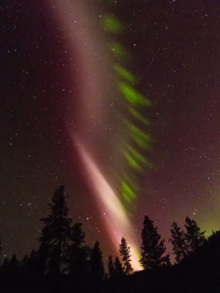 Tall twisted column of pink like beside aurora divided into horizontal pieces.