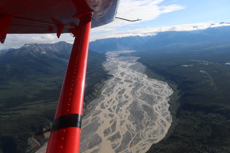 Aerial view of multiple-streamed river with airplane strut in foreground.