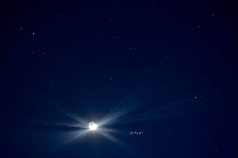Brightly shining crescent moon amidst stars in the west after sunset.