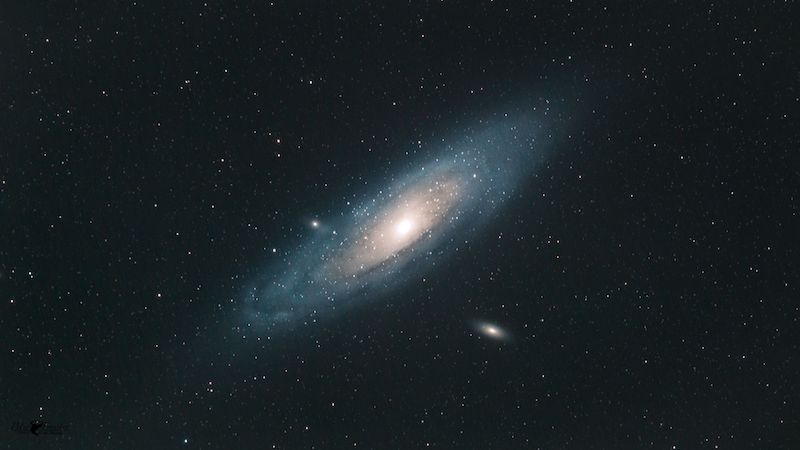 Oblique view of spiral galaxy in dark sky with scattered stars.
