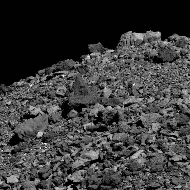 Hill covered with gray rocks and boulders. Black sky.