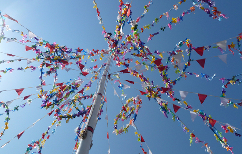 View from below of pole with ribbons which are adorned along their length with tiny flags.