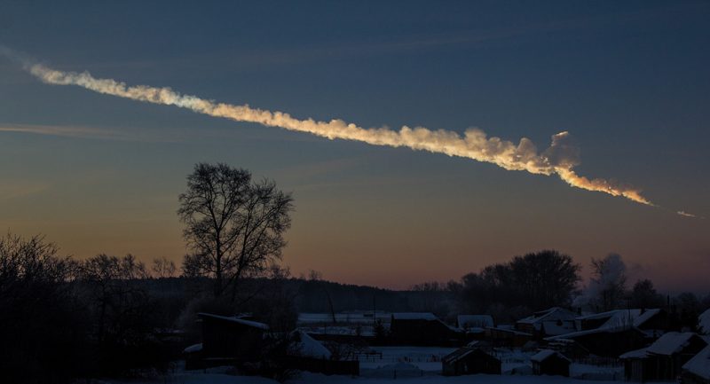 Tunguska explosion: Long billowing trail of white smoke in sky above trees and houses.