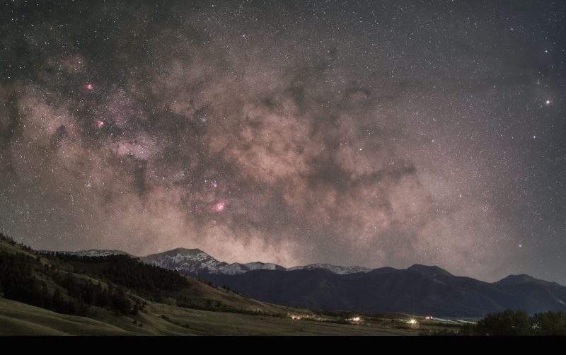 Clouds of Milky Way with very distinct dark rift, over mountains.