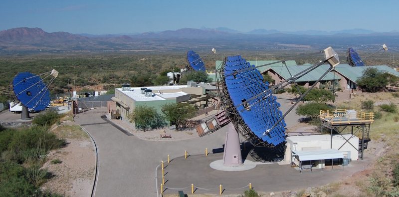 Four bright blue dish-style telescopes and buildings.