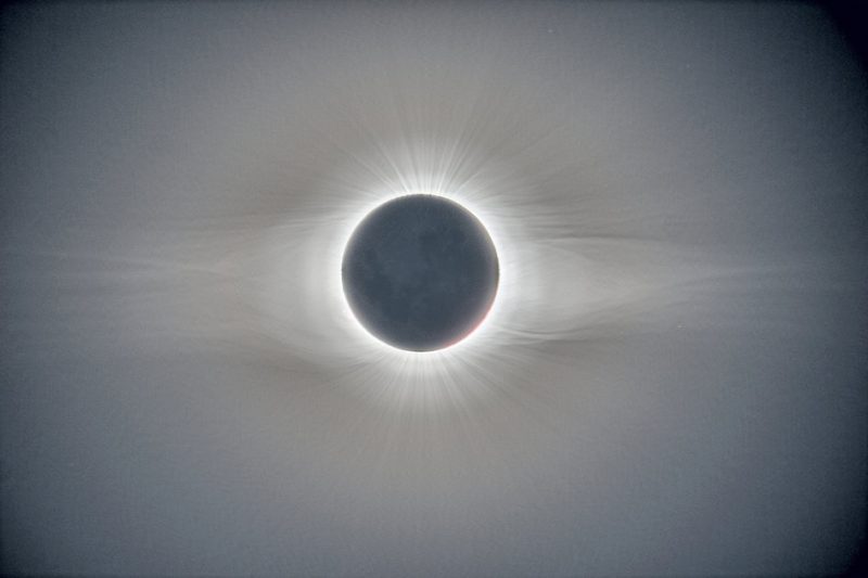 Black circle with fine, delicate white rays coming out, more on the sides.