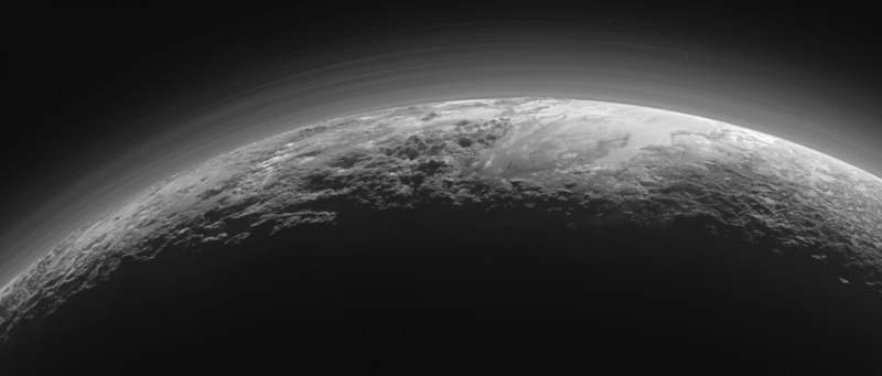 An illuminated edge of Pluto, backlit so that you can see its atmosphere.