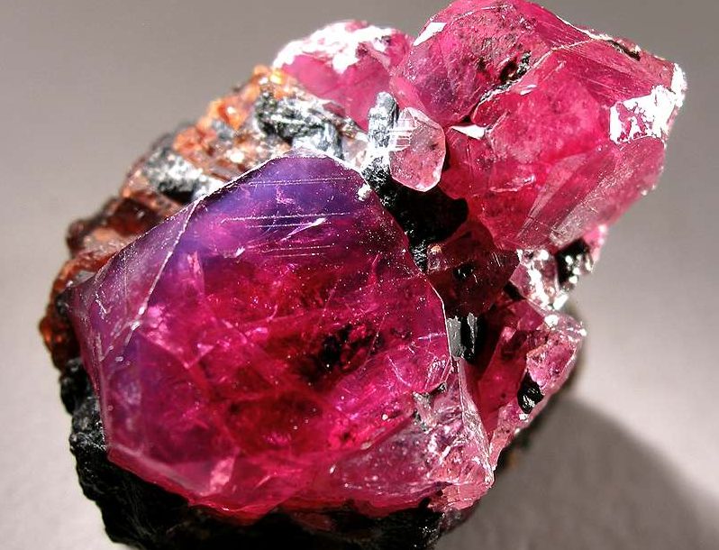A rock with large pink and red crystals embedded in it.