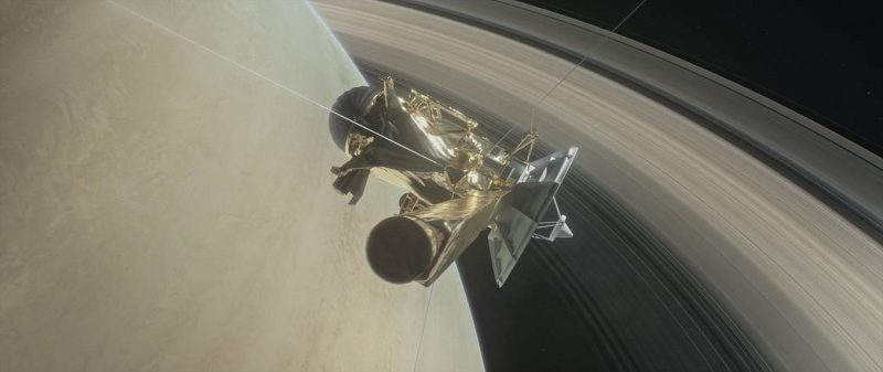 Complex spacecraft with large dish antenna against background of planet and rings.