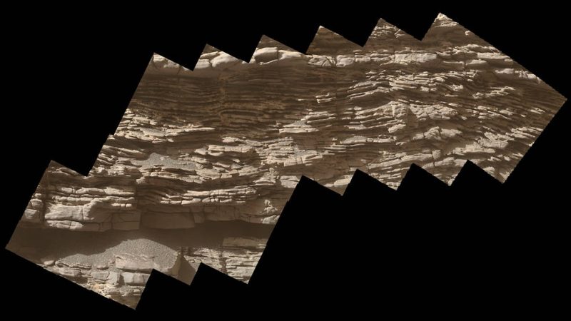 Wavy horizontal striations in dark and light brown across surface of rock.