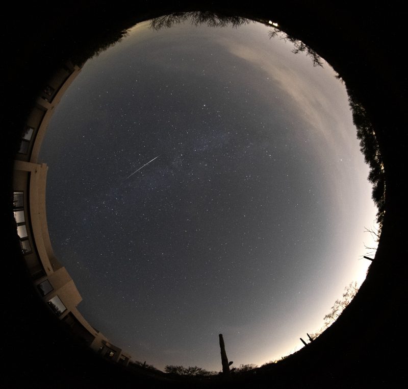 Circular panorama view of the Tucson skyline with sky in the middle and a white streak against the stars.