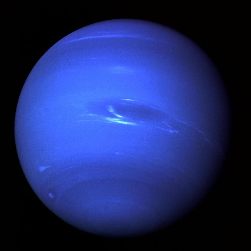 Bright blue planet with oblong darker blue spot partly edged with light blue.
