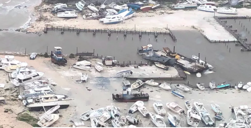 Ocean marina with very many destroyed boats washed up on the land.