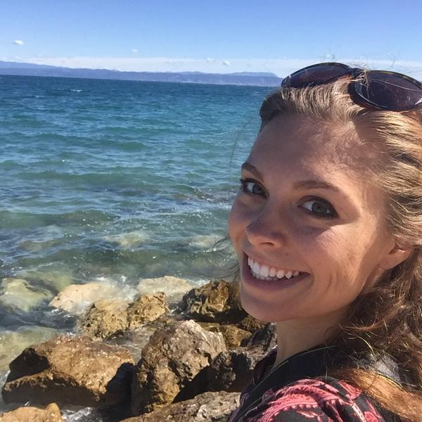 Smiling young woman in front of ocean.