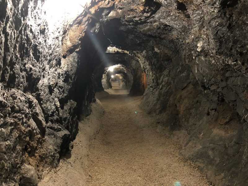 Well-cleared, well-lighted, rocky mining tunnel with flat floor.