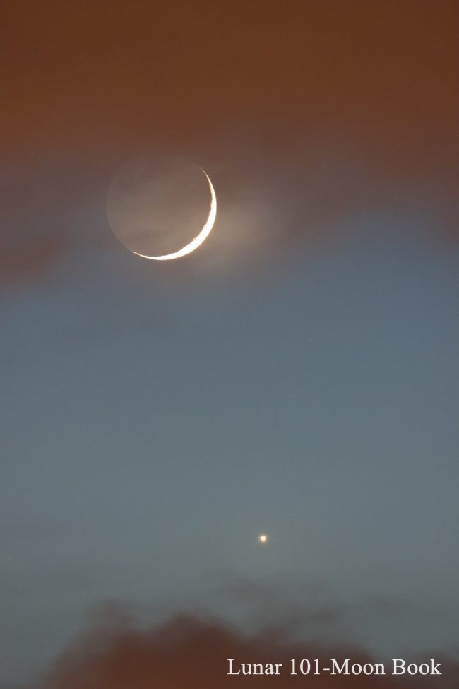 Very thin crescent moon above bright Venus, in a twilight sky.