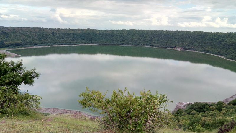 Circular lake surrounded by trees and bushes.