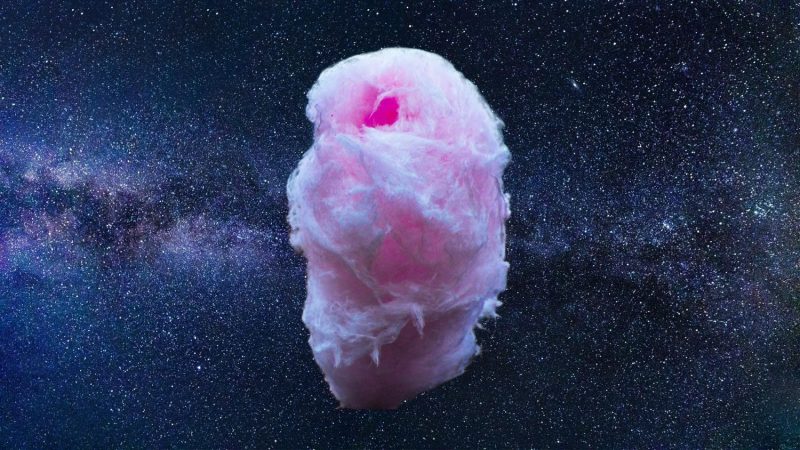 Large irregular wad of fluffy pink substance with thousands of stars behind it.