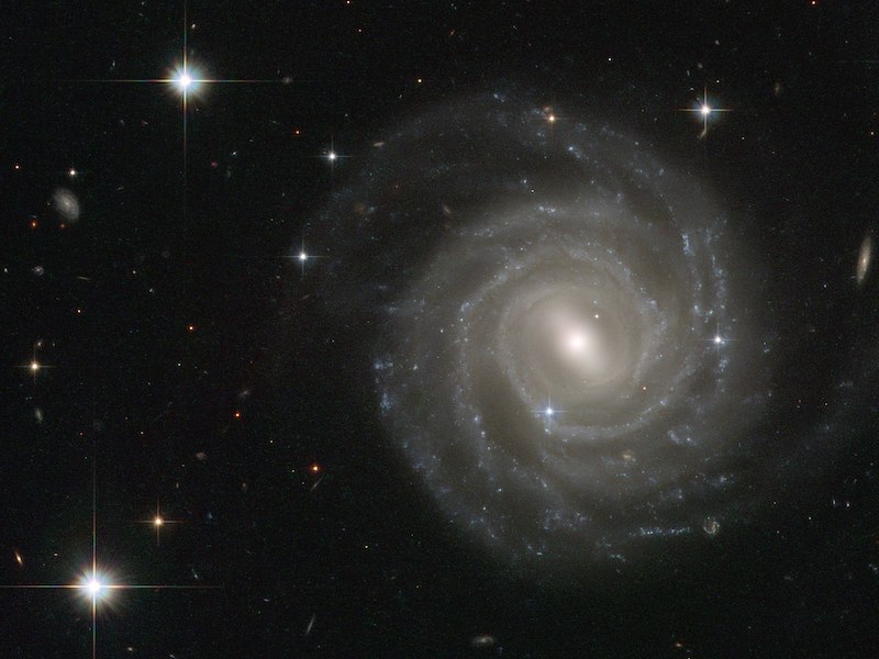 Flat-on view of round spiral galaxy with short bar in the middle.