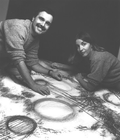 A man and a woman leaning over a table covered with a cosmic-looking graphic.