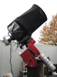 Short, thick telescope with wires trailing from it, standing on mounting outdoors.