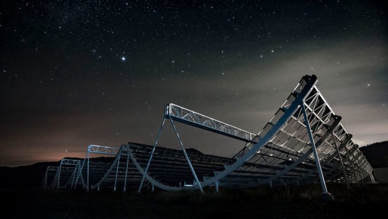 Large curving metallic framework structure under starry sky.