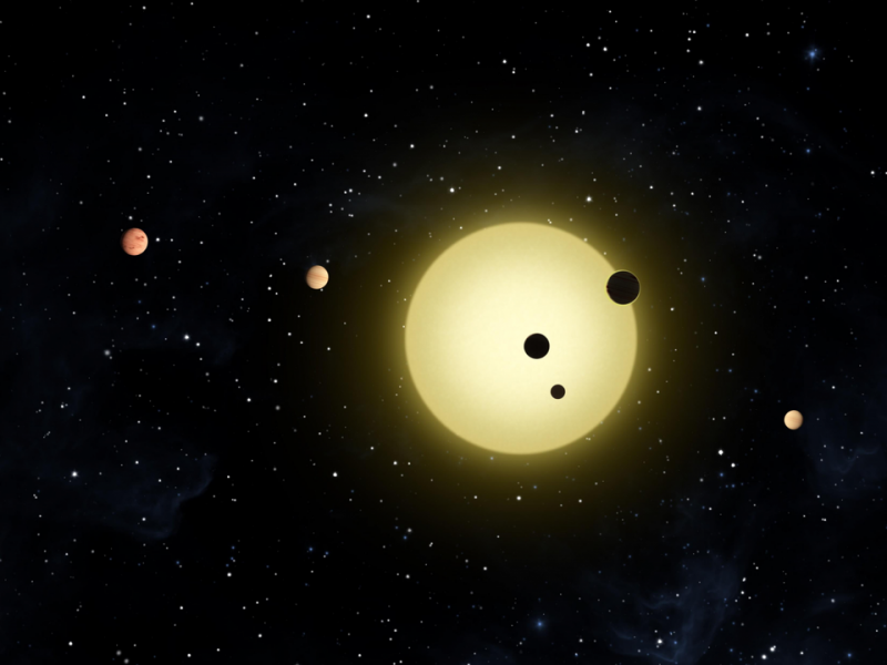 A yellow sunlike star with 4 planets. Two of the planets are 'transiting' or passing in front of the star.