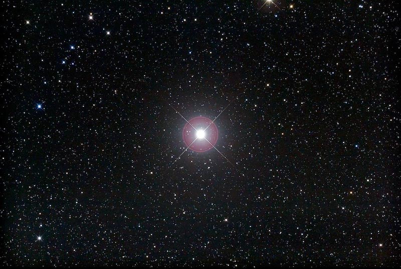 Afbeelding van de heldere ster Pollux tegen een achtergrond van vele zwakkere sterren.