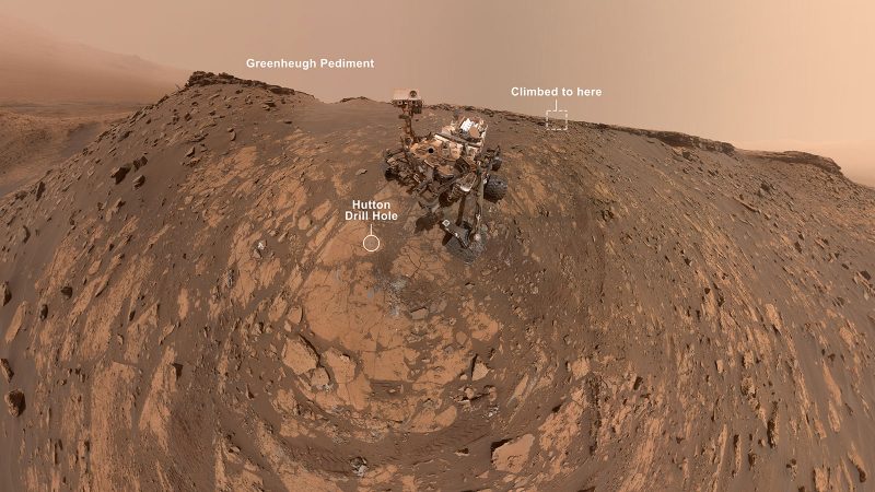 Mechanical rover in middle of brownish rocky landscape, with text annotations.
