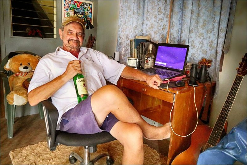 Man lounging in desk chair holding a bottle of whiskey.