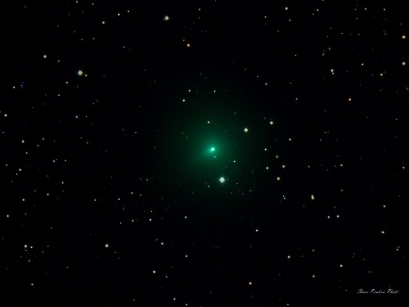 A fuzzy green little slightly oblong comet in front of the stars.
