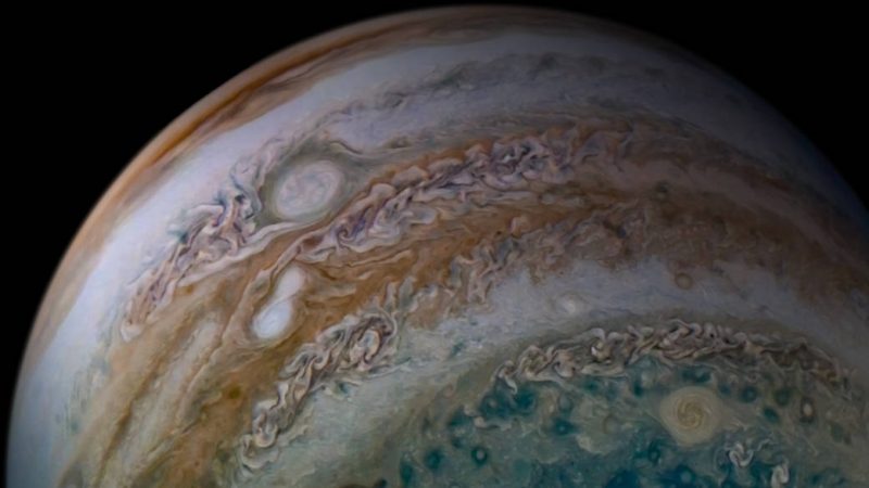 Partial orbital view of Jupiter with two relatively small white ovals overlapping.