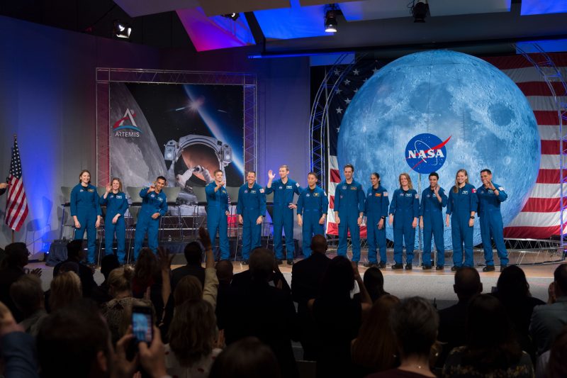 A line of people in blue jumpsuits standing on a stage.