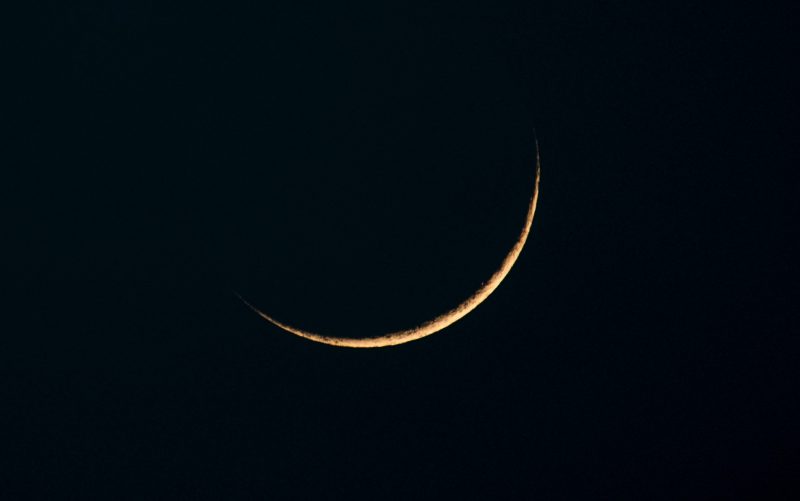 Thin yellow crescent on black background.
