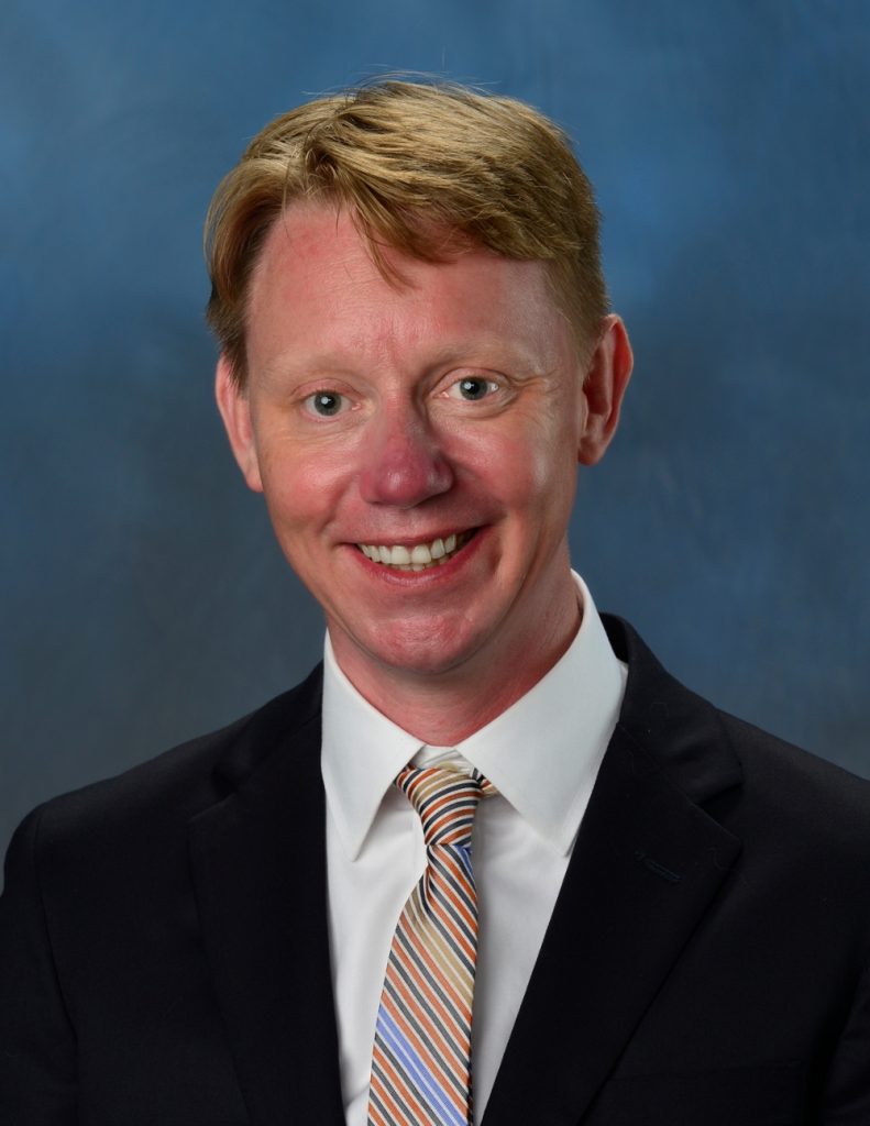 Smiling man in suit on blue background.