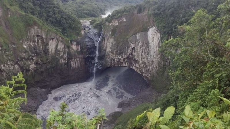 Trickle of water flowing down rocks into scummy-looking pool.