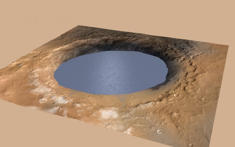 Large round hole in reddish orange landscape filled with water and ringed by crater edges.