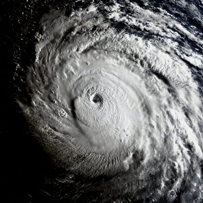 Close-up orbital view of giant hurricane with many spiral arms and small central eye at sunrise.