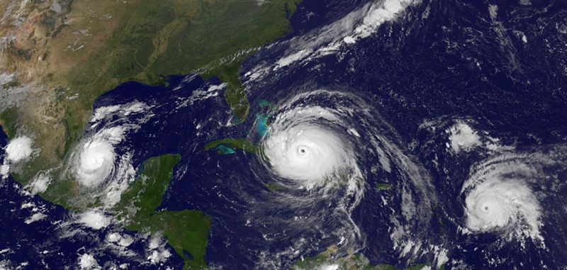 Satellite image of 3 hurricanes in the Allantic ocean with North America to left.