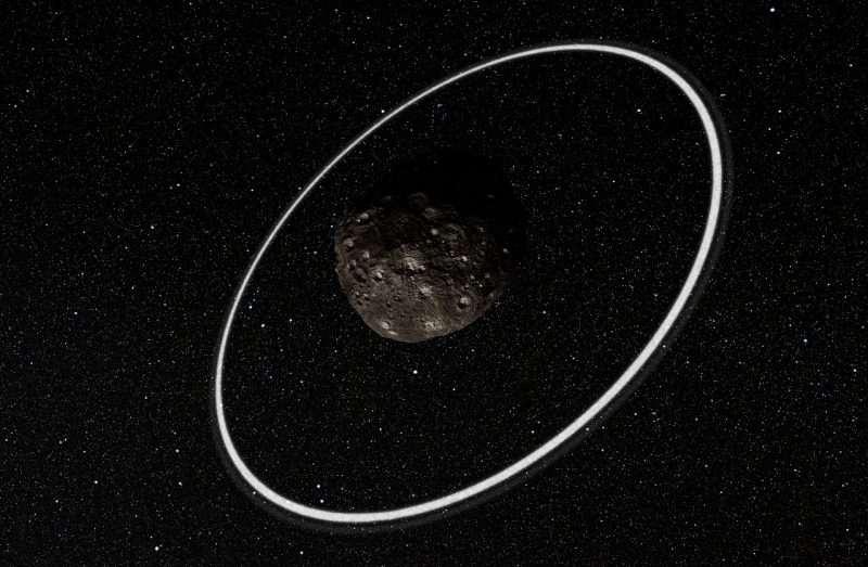 Dark rocky object with narrow bright ring around it and stars in background.