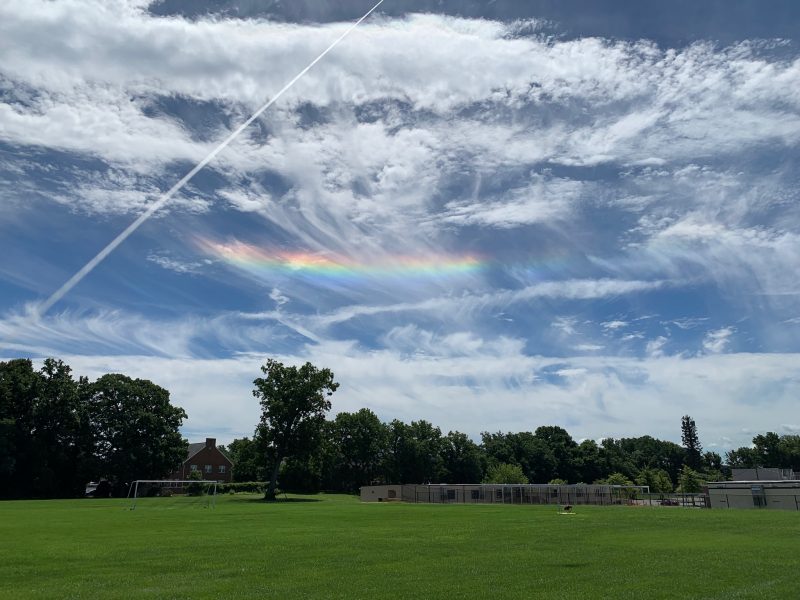 Wispy clouds with a rainbow streak parallel to the horizon.