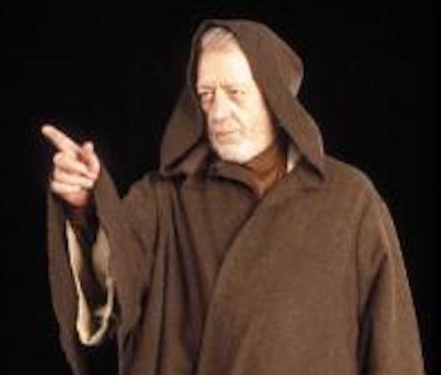 Old man with short white beard wearing a brown hooded robe.